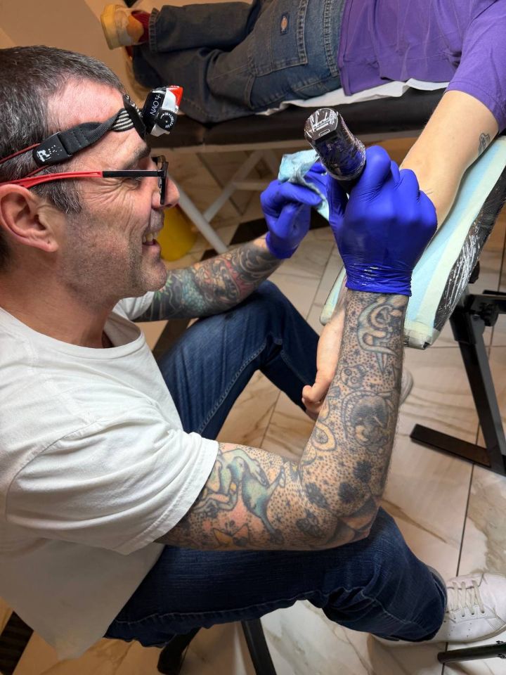 Un artista di UnderSkin al lavoro con lente d'ingrandimento e guanti blu